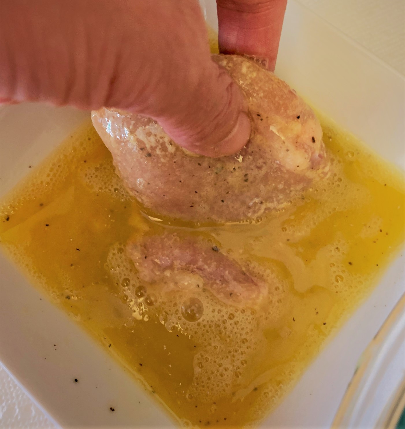 Dipping the chicken into the egg-wash