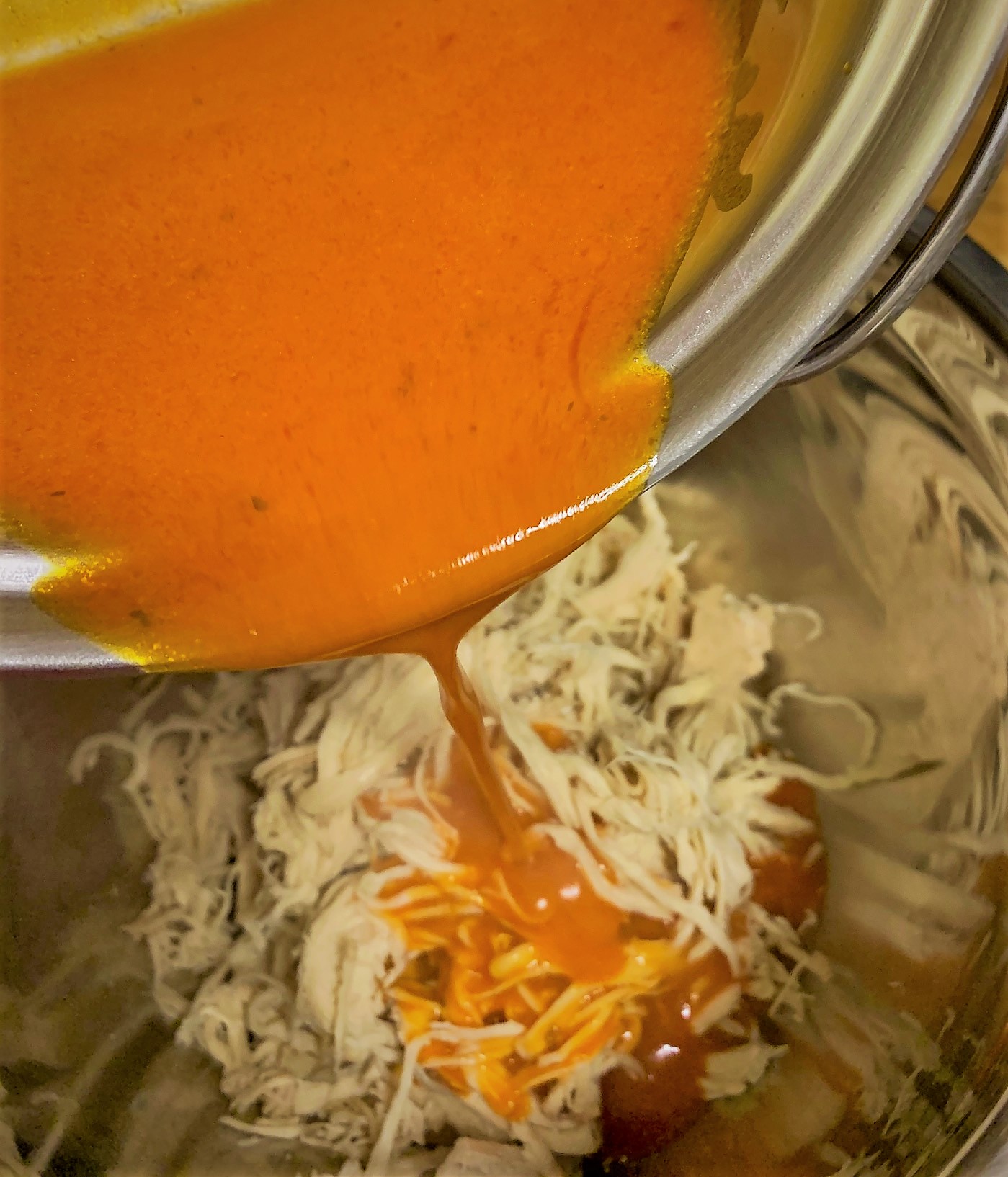 Adding the Buffalo Sauce to the Shredded Chicken