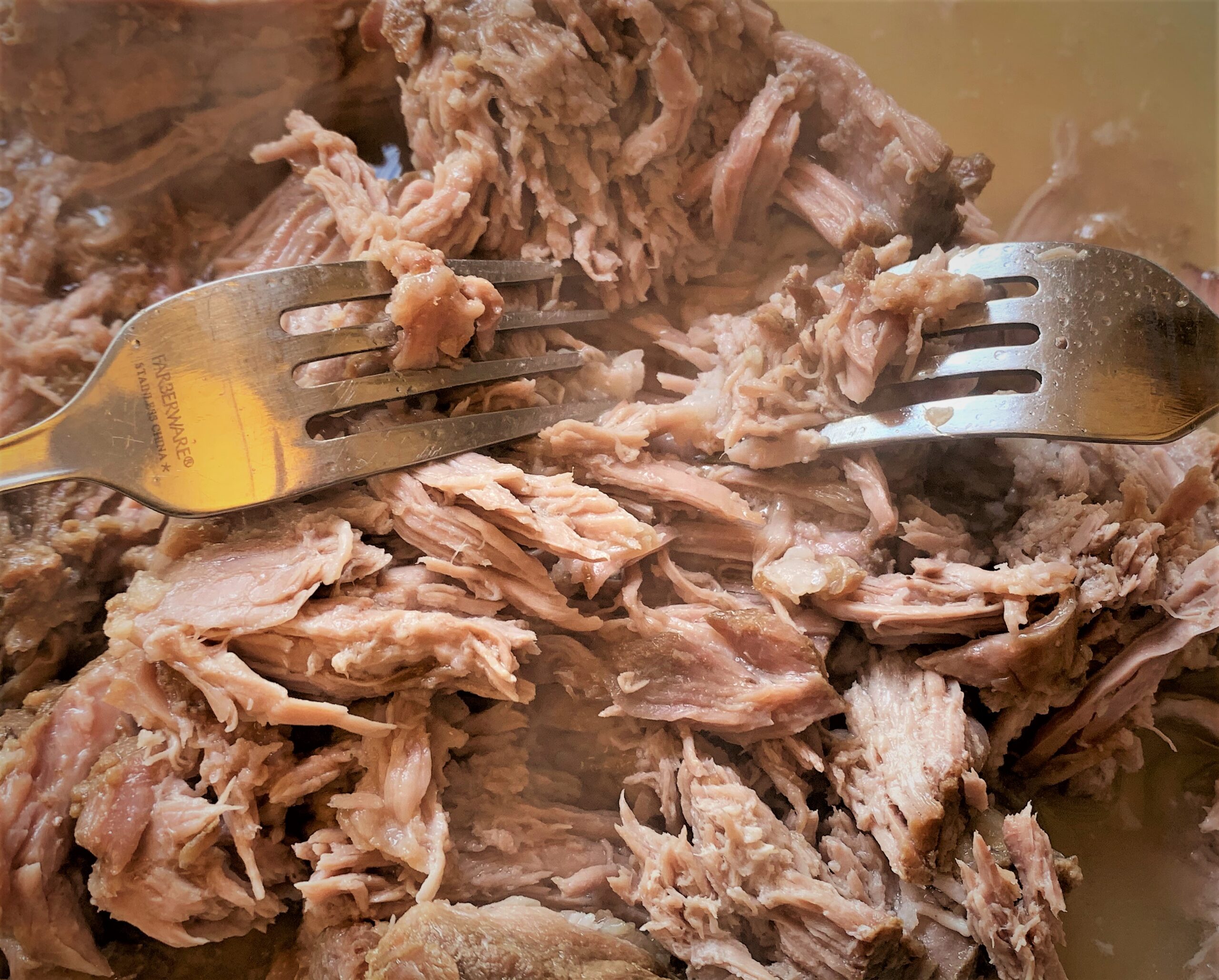 Using forks to pull the meat for our Kalua-Style Pulled Pork Tots with Polynesian BBQ Sauce & Mango Salsa