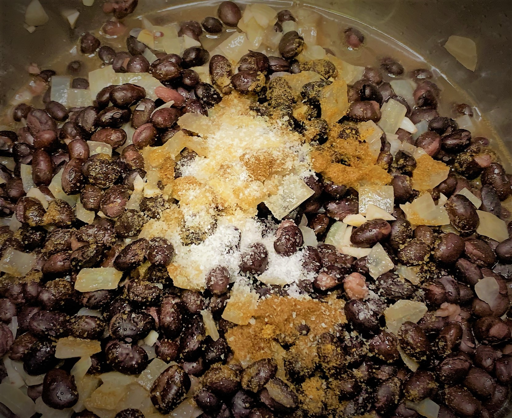 Cumin, Salt and Pepper added to the Black Beans for our Tostada de Chorizo from Las Posadas Holiday Kitchen