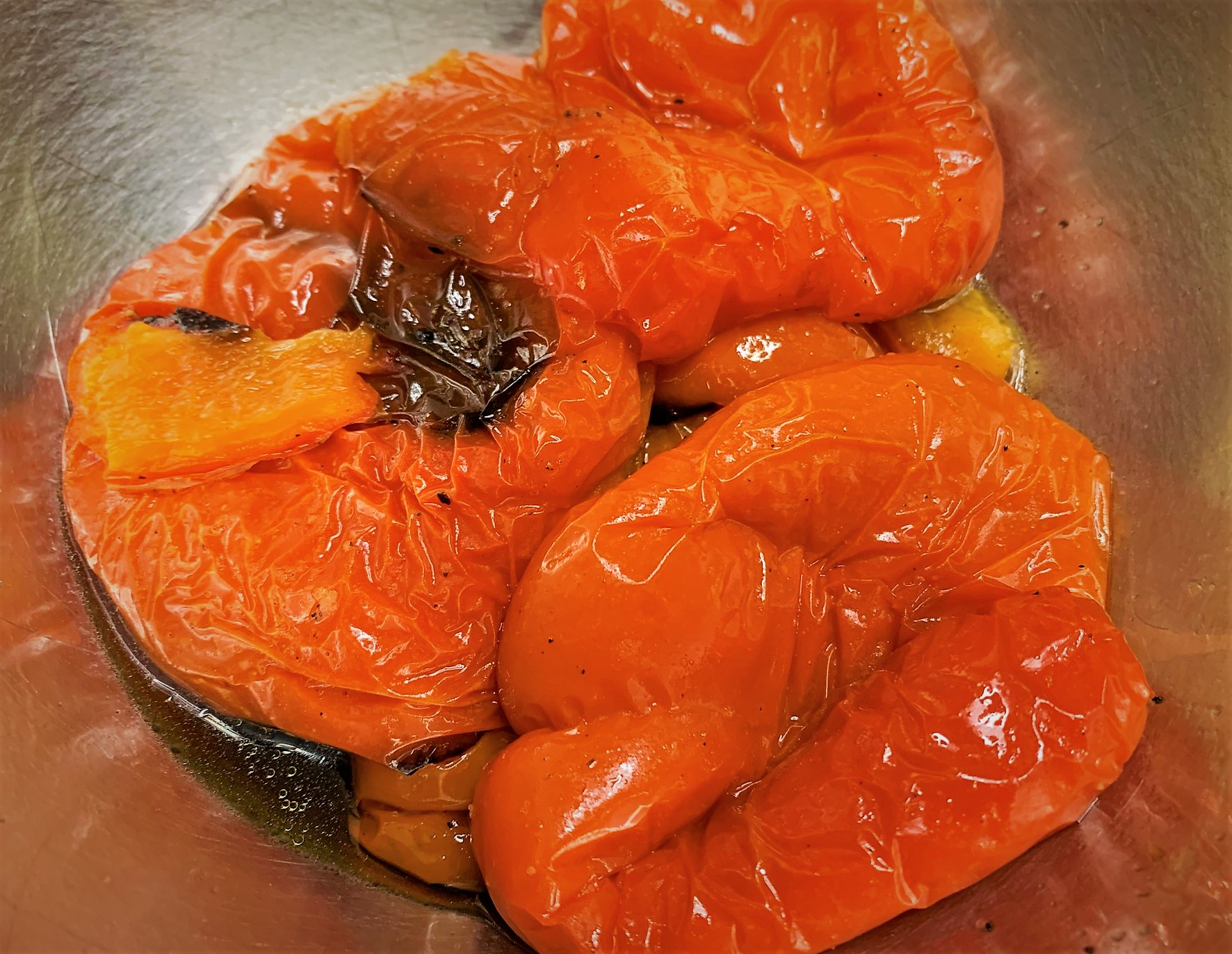 The Roasted Red Bell Peppers in a bowl and ready to be peeled